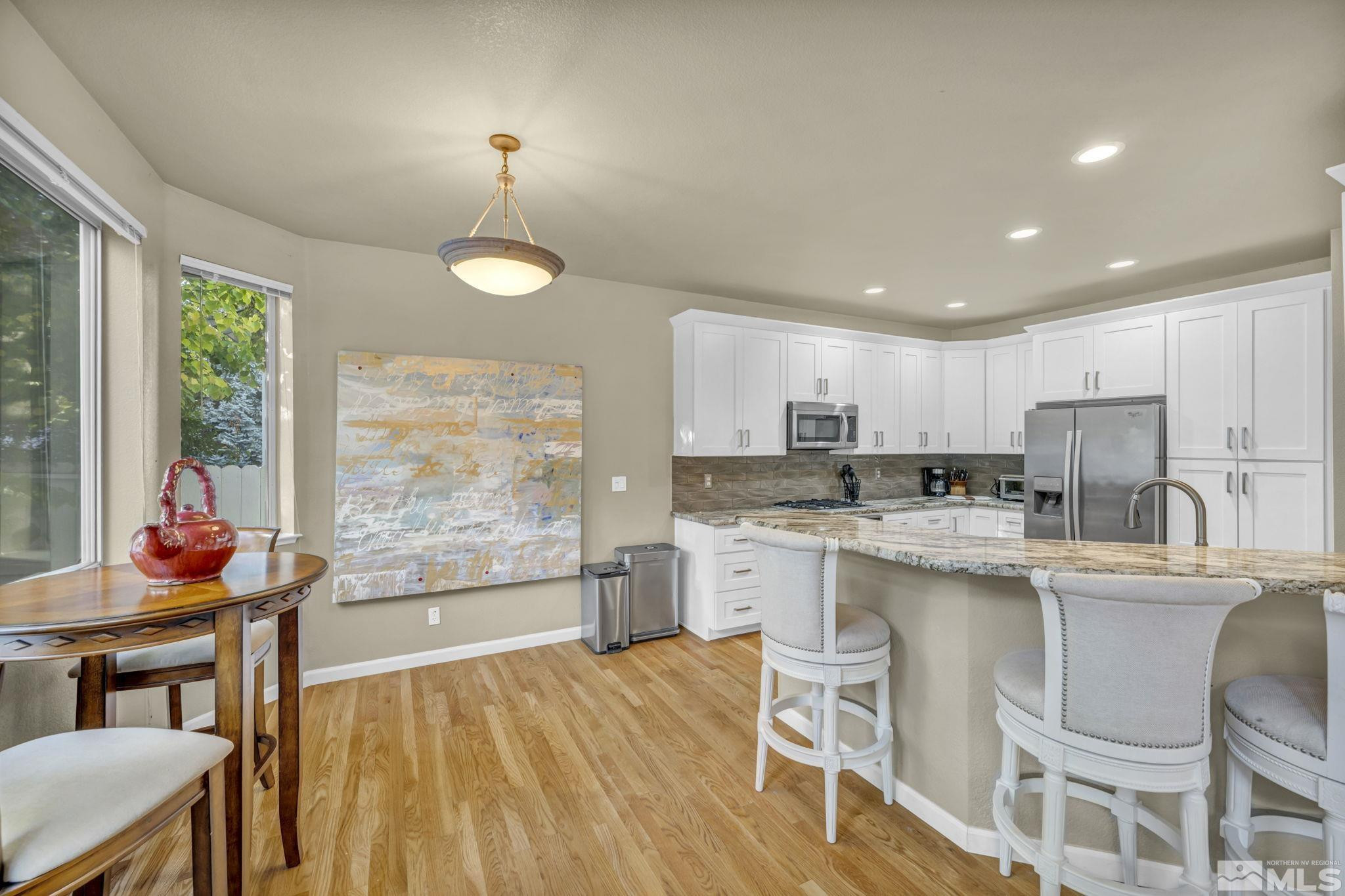 4731 Ellicott Way Reno, NV 89519 - Photo 8 of 36 a kitchen with stainless steel appliances granite countertop a stove a refrigerator a kitchen island a dining table and chairs