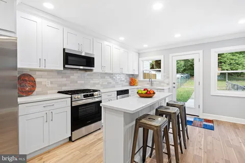 a kitchen with a sink a stove and white cabinets