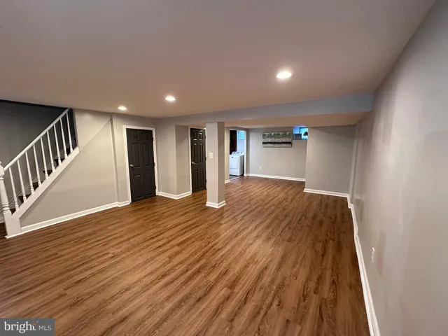 a view of an empty room with wooden floor and staircase