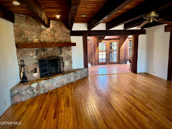 a view of an empty room with wooden floor fireplace and a window