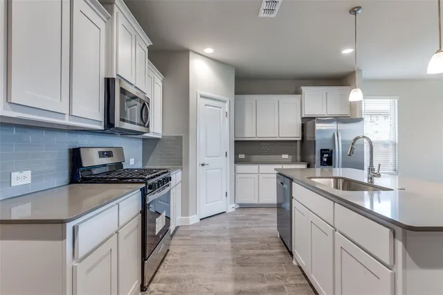 a kitchen with stainless steel appliances granite countertop a sink stove refrigerator and cabinets