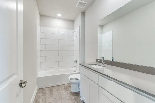 a bathroom with a granite countertop sink a toilet and bathtub