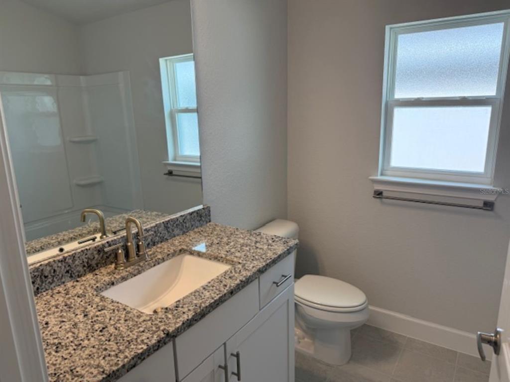 2150 Northwest 23rd Loop Ocala, FL 34475 - Photo 12 of 19 a bathroom with a granite countertop sink a mirror and a toilet