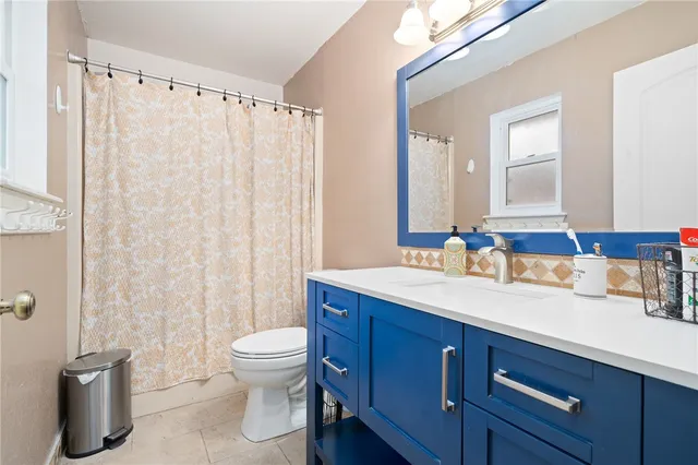 a bathroom with a granite countertop sink toilet a mirror and shower curtain