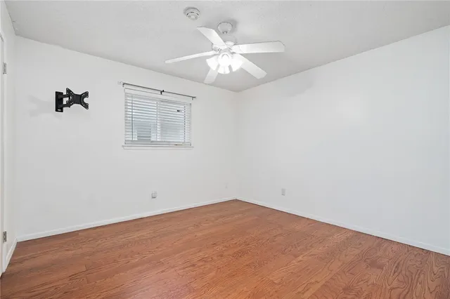 an empty room with a chandelier fan and windows