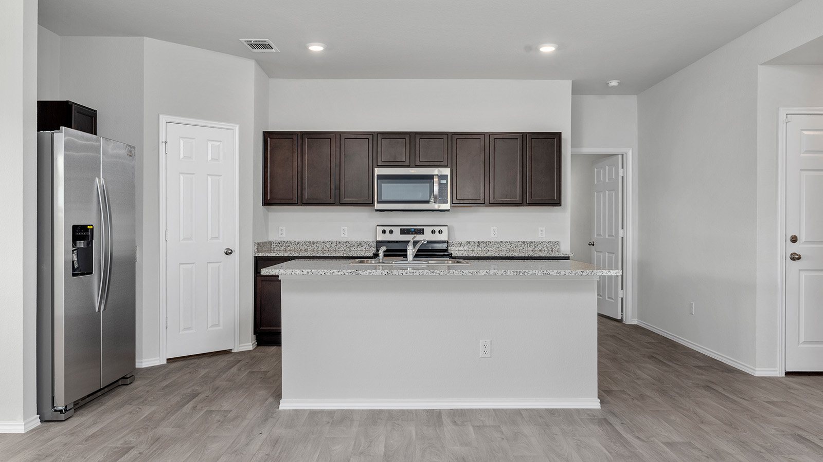 1320 Victory Rnch Trail Killeen, TX 76549 - Photo 6 of 22 Kitchen featuring stainless steel appliances, a kitchen island with sink, light stone counters, and dark wood finish cabinetry