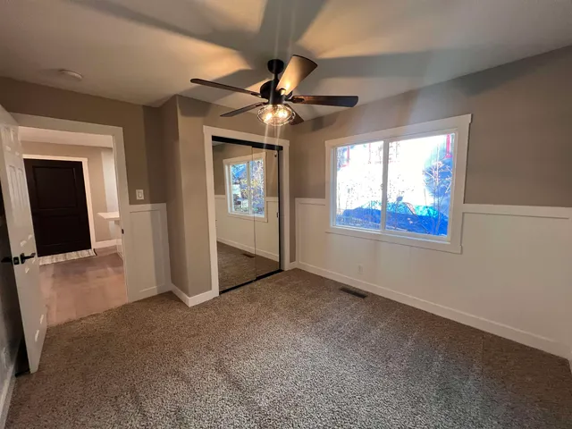 an empty room with windows and fan