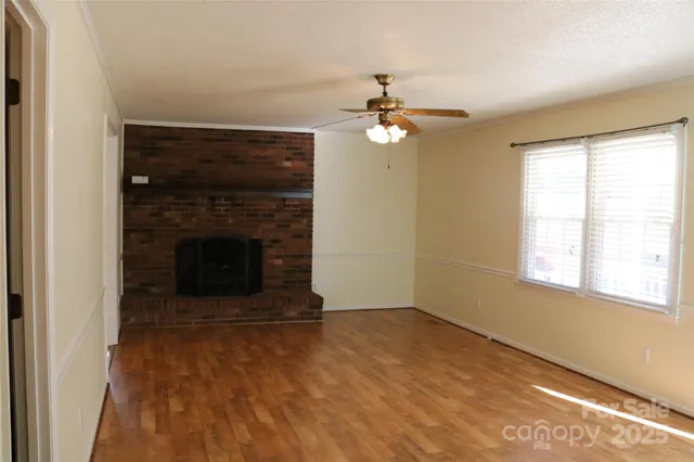 an empty room with windows and fireplace
