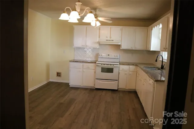 a kitchen with cabinets a sink dishwasher and a stove with wooden floor