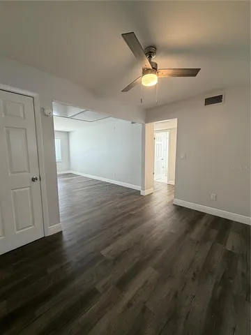 a view of an empty room with wooden floor and a ceiling fan
