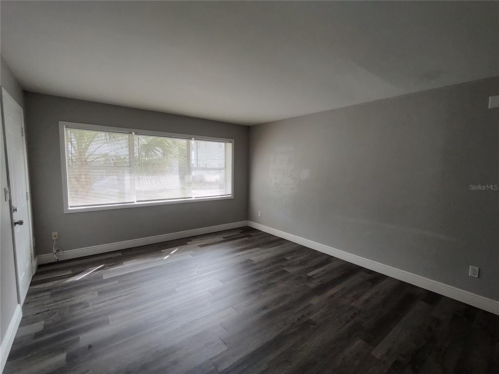 320 West Howry Avenue, Unit 1 Deland, FL 32720 - Photo 13 of 33 a view of an empty room with wooden floor and a window