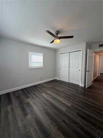 a view of an empty room with wooden floor and a ceiling fan