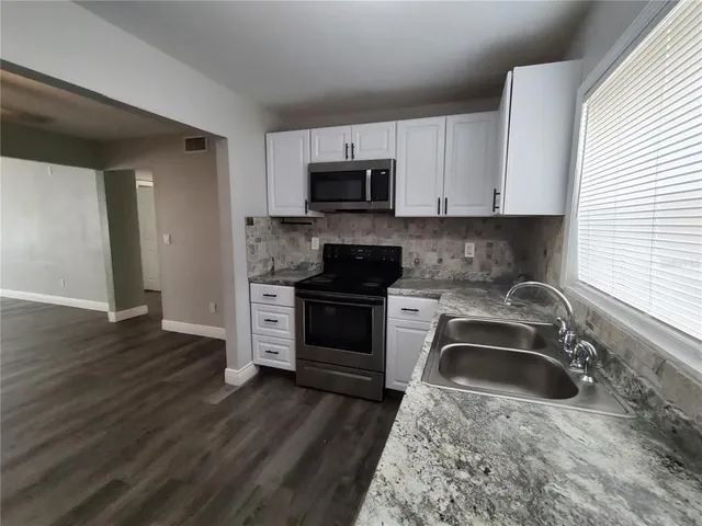 a kitchen with granite countertop a sink and a stove top oven