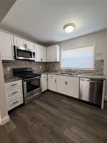 a kitchen with stainless steel appliances granite countertop a stove top oven a sink and white cabinets