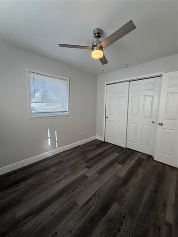 an empty room with wooden floor a ceiling fan and windows