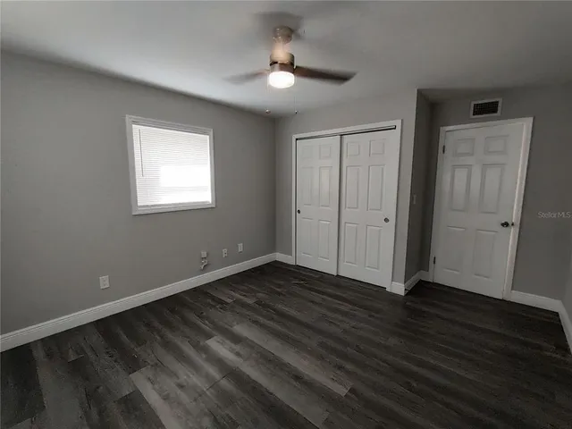 an empty room with wooden floor cabinet and windows