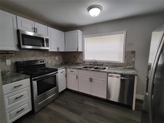 a kitchen with stainless steel appliances granite countertop a stove a sink and a microwave