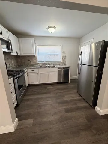 a kitchen with granite countertop a refrigerator stove and sink