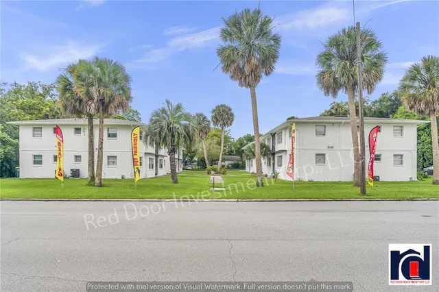 a front view of a house with a yard and palm trees