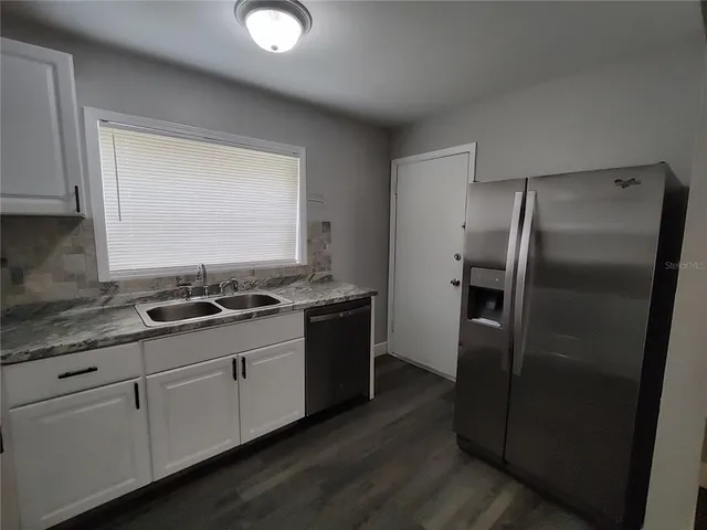 a kitchen with stainless steel appliances granite countertop a refrigerator a sink and a stove