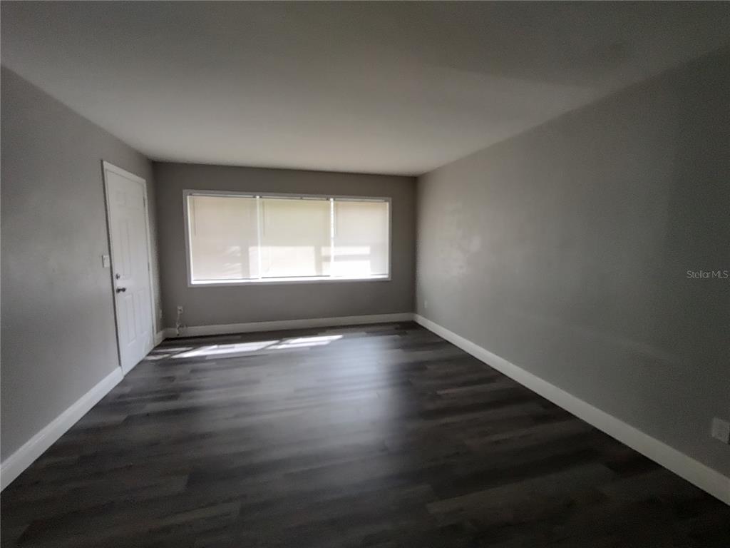 320 West Howry Avenue, Unit 1 Deland, FL 32720 - Photo 9 of 33 an empty room with wooden floor and windows