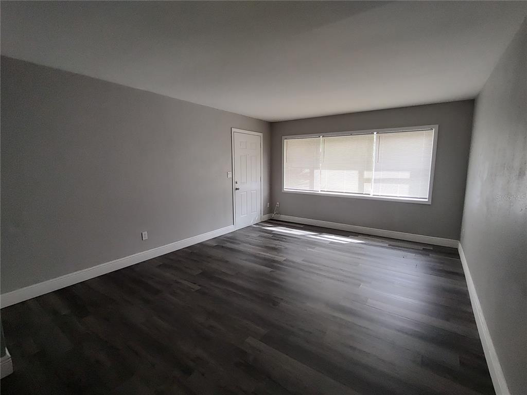 320 West Howry Avenue, Unit 1 Deland, FL 32720 - Photo 10 of 33 an empty room with wooden floor and windows