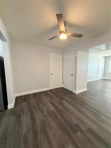 an empty room with wooden floor and ceiling fan