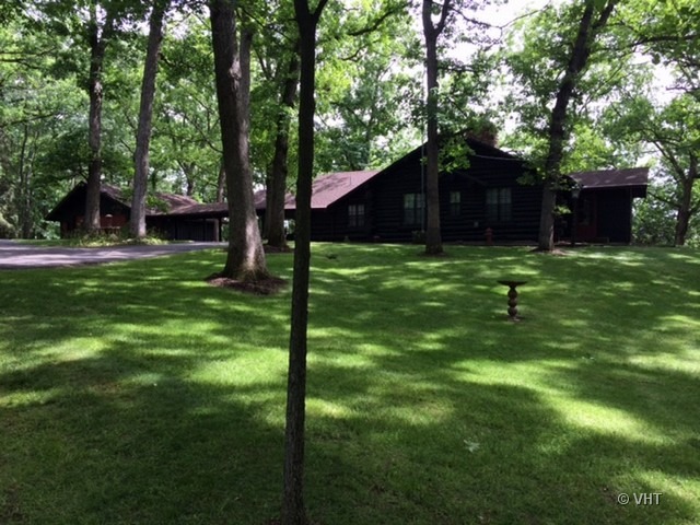 a backyard of a house with table and chairs plants and large tree