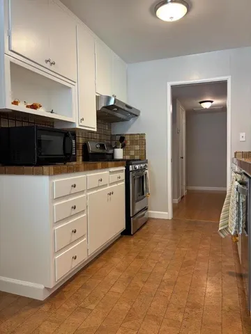 a kitchen with granite countertop a stove a sink and a microwave