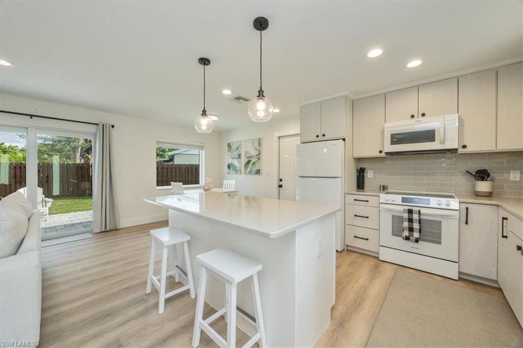3560 Corana Way Naples, FL 34105 - Photo 5 of 24 a kitchen with stainless steel appliances kitchen island a table chairs sink and cabinets