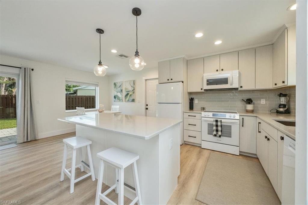 3560 Corana Way Naples, FL 34105 - Photo 6 of 24 a kitchen with stainless steel appliances kitchen island granite countertop a stove a sink and a refrigerator