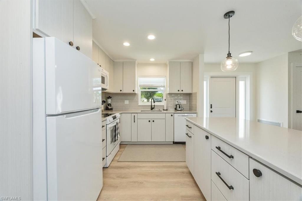 3560 Corana Way Naples, FL 34105 - Photo 7 of 24 a kitchen with white cabinets and white appliances