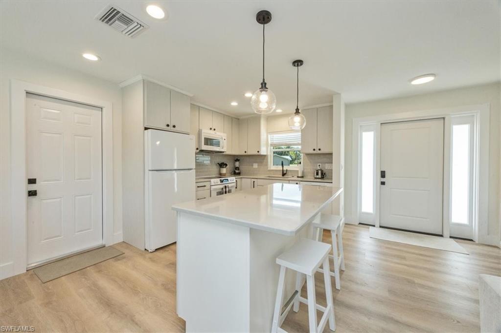3560 Corana Way Naples, FL 34105 - Photo 8 of 24 a kitchen with stainless steel appliances kitchen island granite countertop a refrigerator a sink a stove and white cabinets with wooden floor