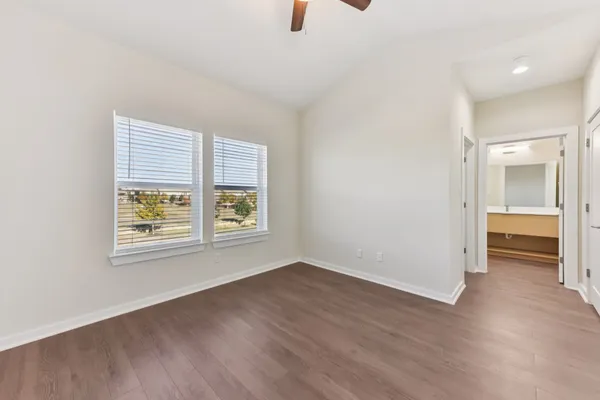 an empty room with wooden floor and ceiling fan