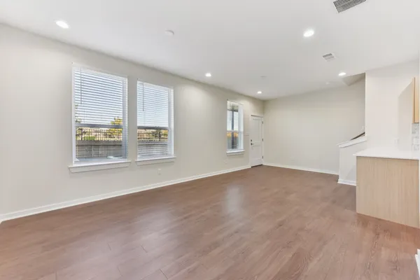 a view of an empty room with a window and wooden floor