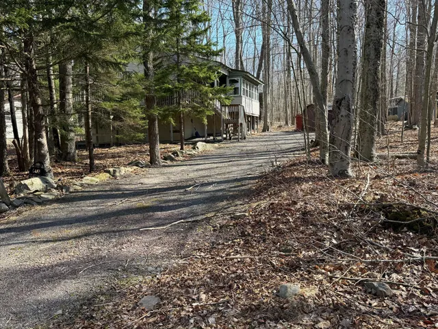 a view of a backyard with large trees and a barn