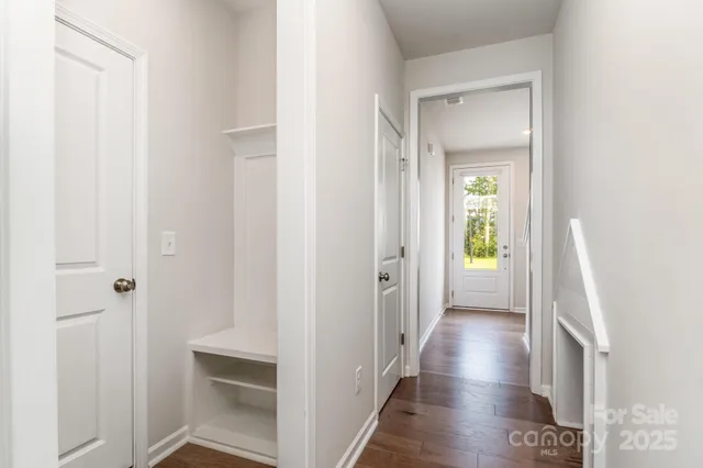 a view of a hallway with wooden floor and a bathroom