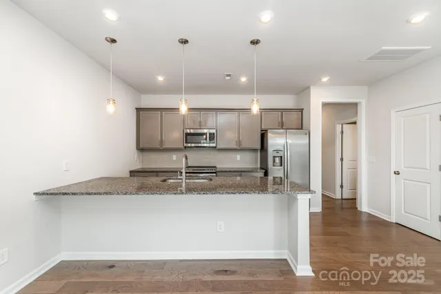 a large kitchen with stainless steel appliances granite countertop a large counter top a sink and a refrigerator