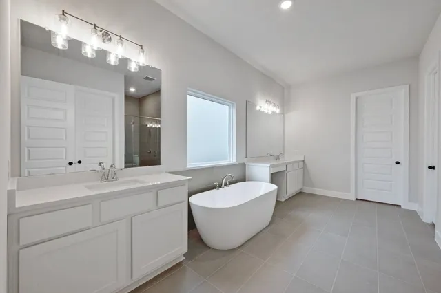 a bathroom with a double vanity sink mirror and bathtub