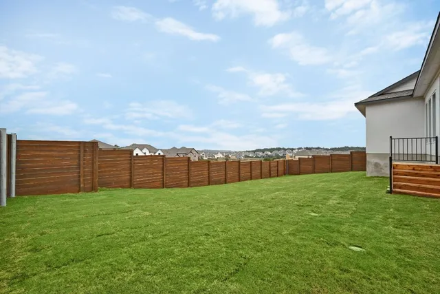 a view of a yard with wooden fence