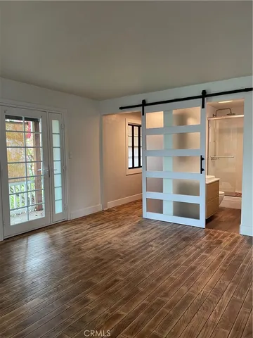 a view of an empty room with a window and wooden floor