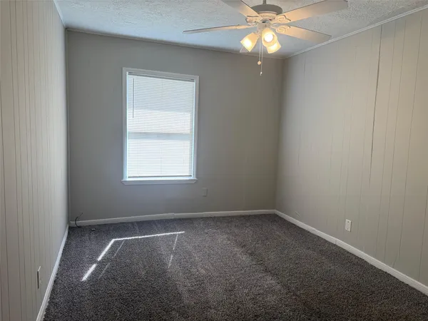 an empty room with a window and a fan