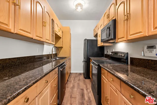 a kitchen with granite countertop a sink a stove and cabinets