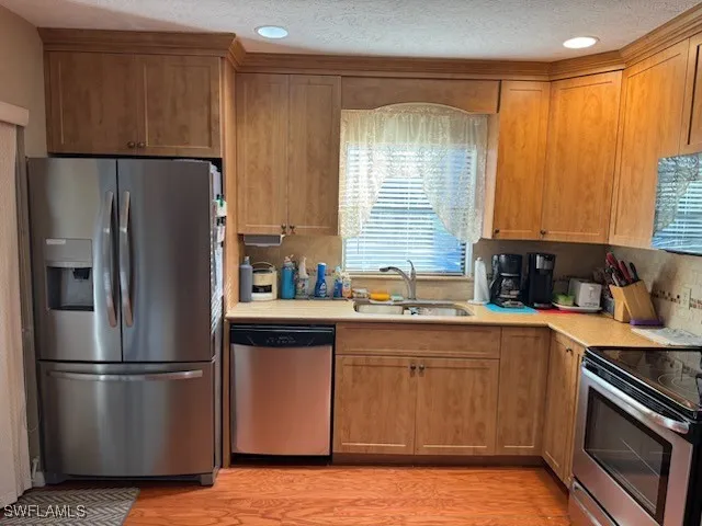 a kitchen with stainless steel appliances granite countertop a refrigerator a sink a stove and a refrigerator