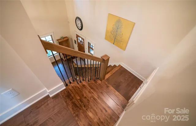 a view of a hallway with wooden floor and stairs