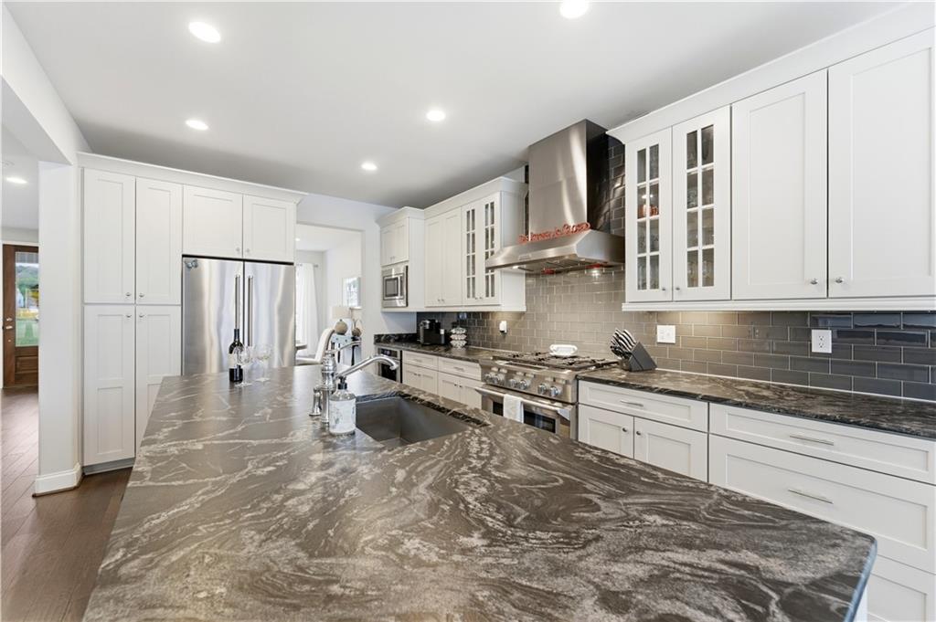1502 Orion Road Bridgeville, PA 15017 - Photo 12 of 46 a large white kitchen with stainless steel appliances granite countertop a stove a sink a refrigerator and white cabinets with wooden floor