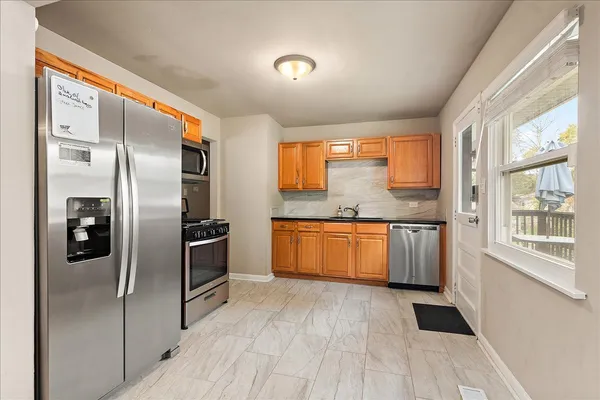 a kitchen with stainless steel appliances granite countertop a refrigerator a sink a stove and oven with wooden floor