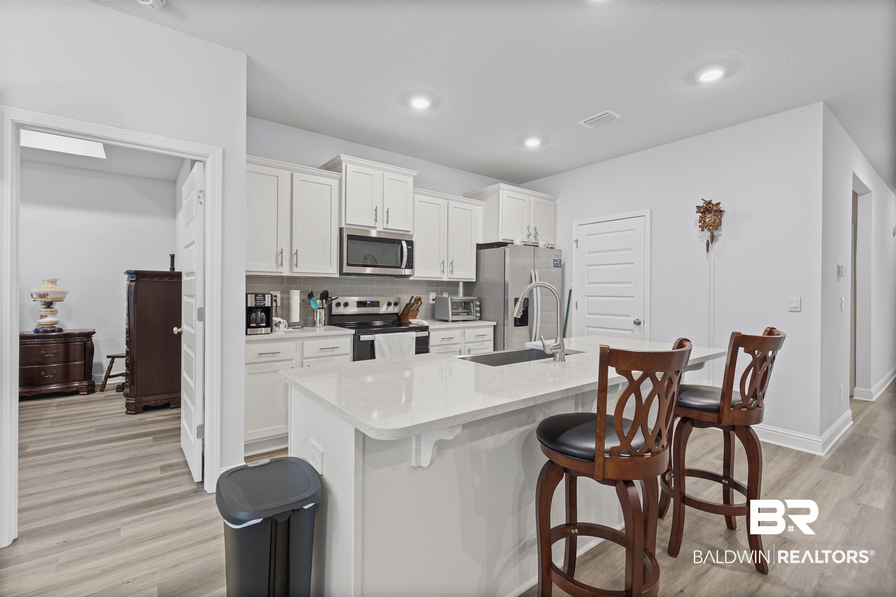 10564 Heirloom Road South Mobile, AL 36608 - Photo 8 of 24 Kitchen featuring backsplash, white cabinetry, appliances with stainless steel finishes, a kitchen bar, and light wood-style flooring