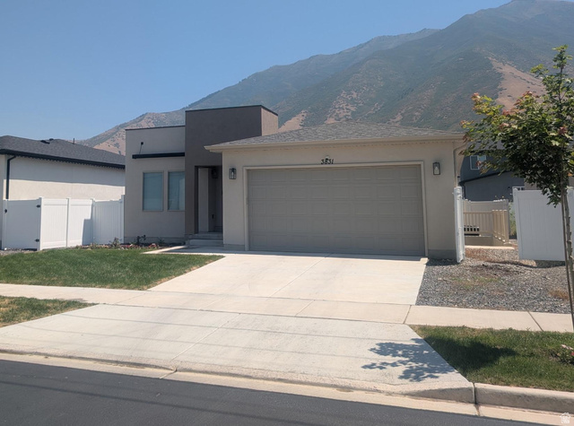 3831 South Powderwood Lane Mapleton, UT 84664 - Photo 1 of 17 Contemporary stucco exterior featuring a two-car garage, concrete driveway, and front lawn