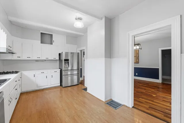 a kitchen with stainless steel appliances white cabinets and wooden floors